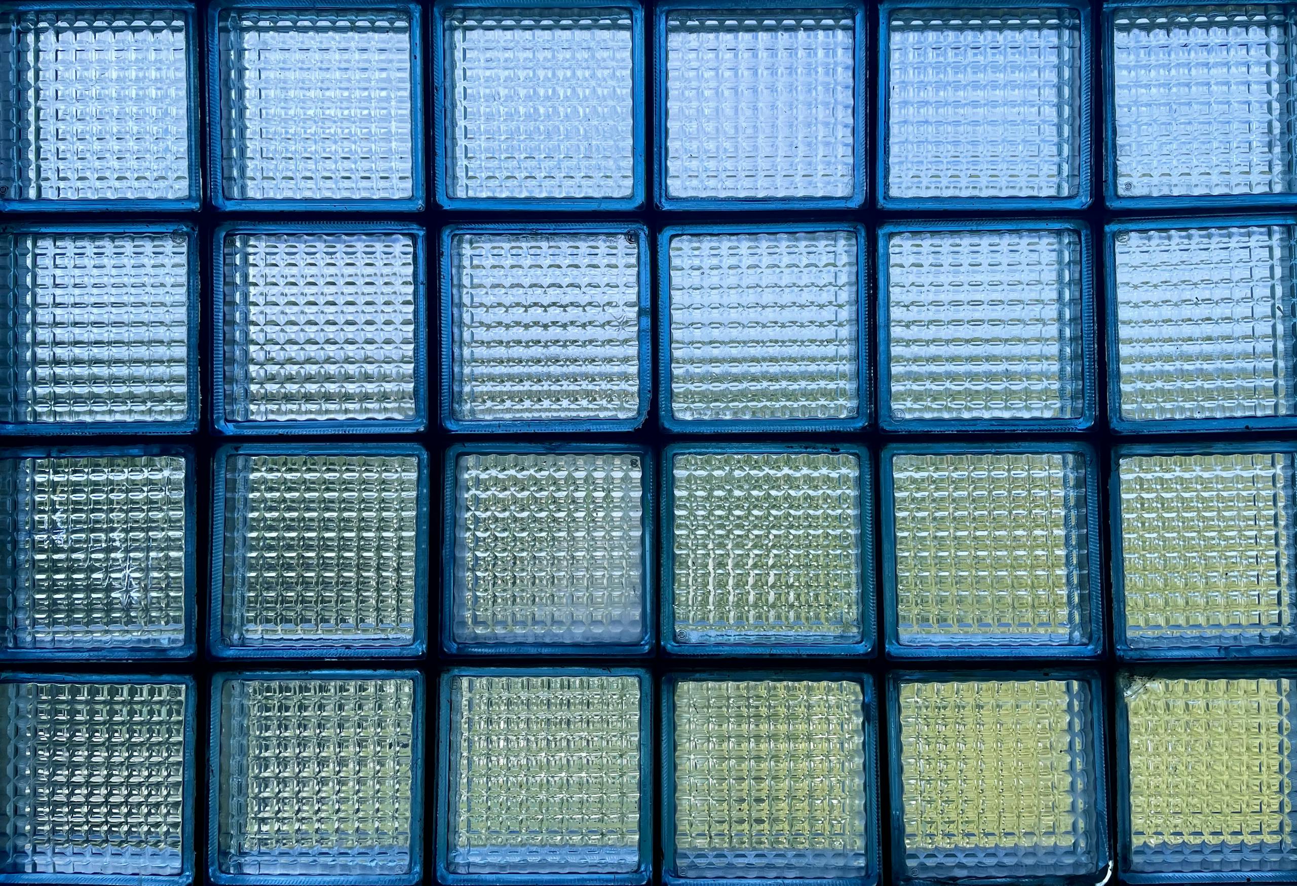 Abstract view of a glass block window with a blue tint, showcasing light and pattern.