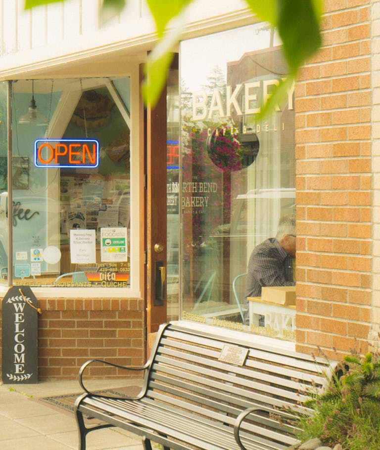 Cozy Seattle bakery storefront with an open sign and welcoming bench. Perfect local atmosphere.