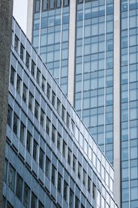 Low angle view of modern glass skyscrapers reflecting the sky in a bustling city.