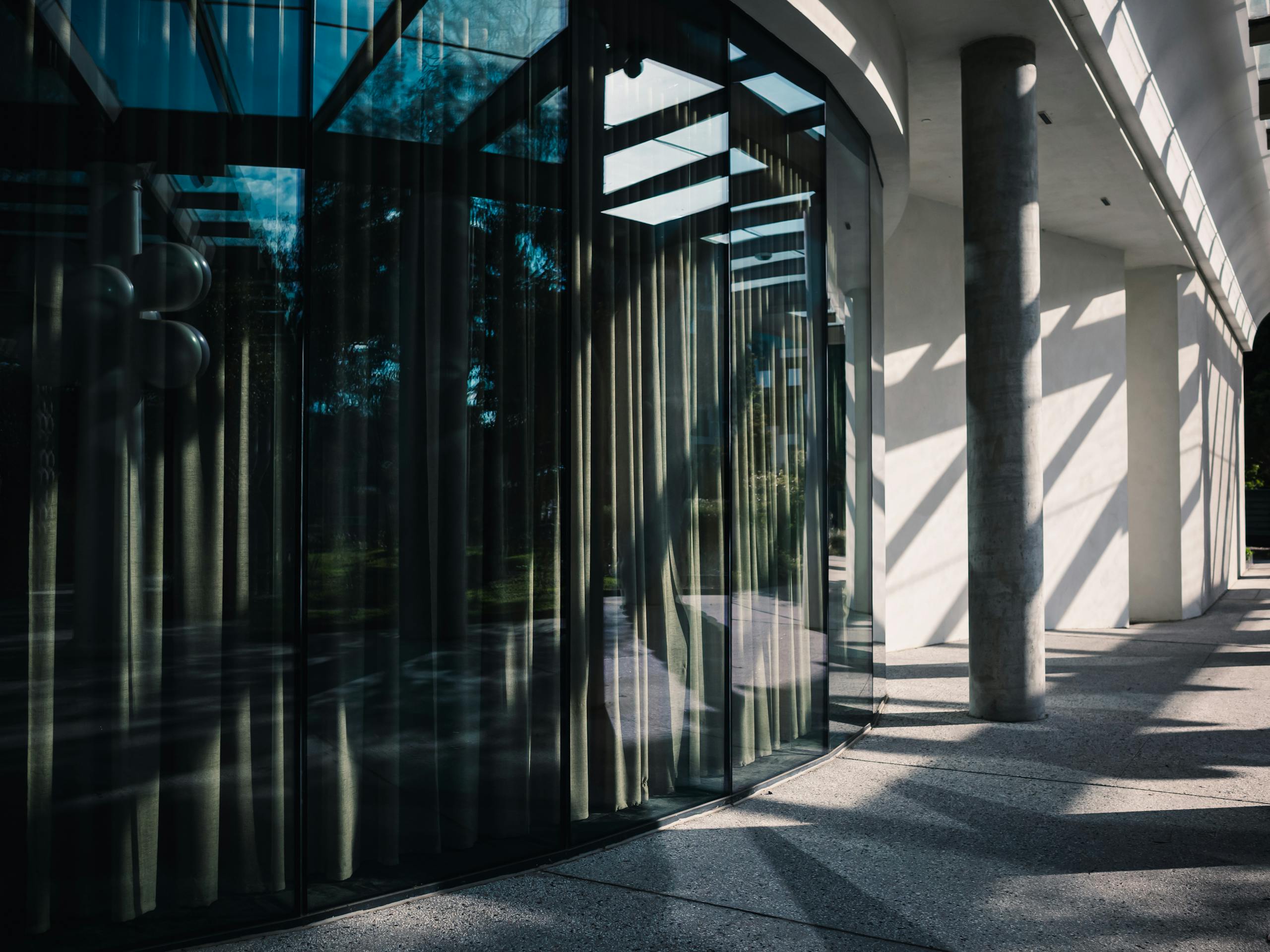 Minimalist urban architecture featuring glass reflections and concrete columns