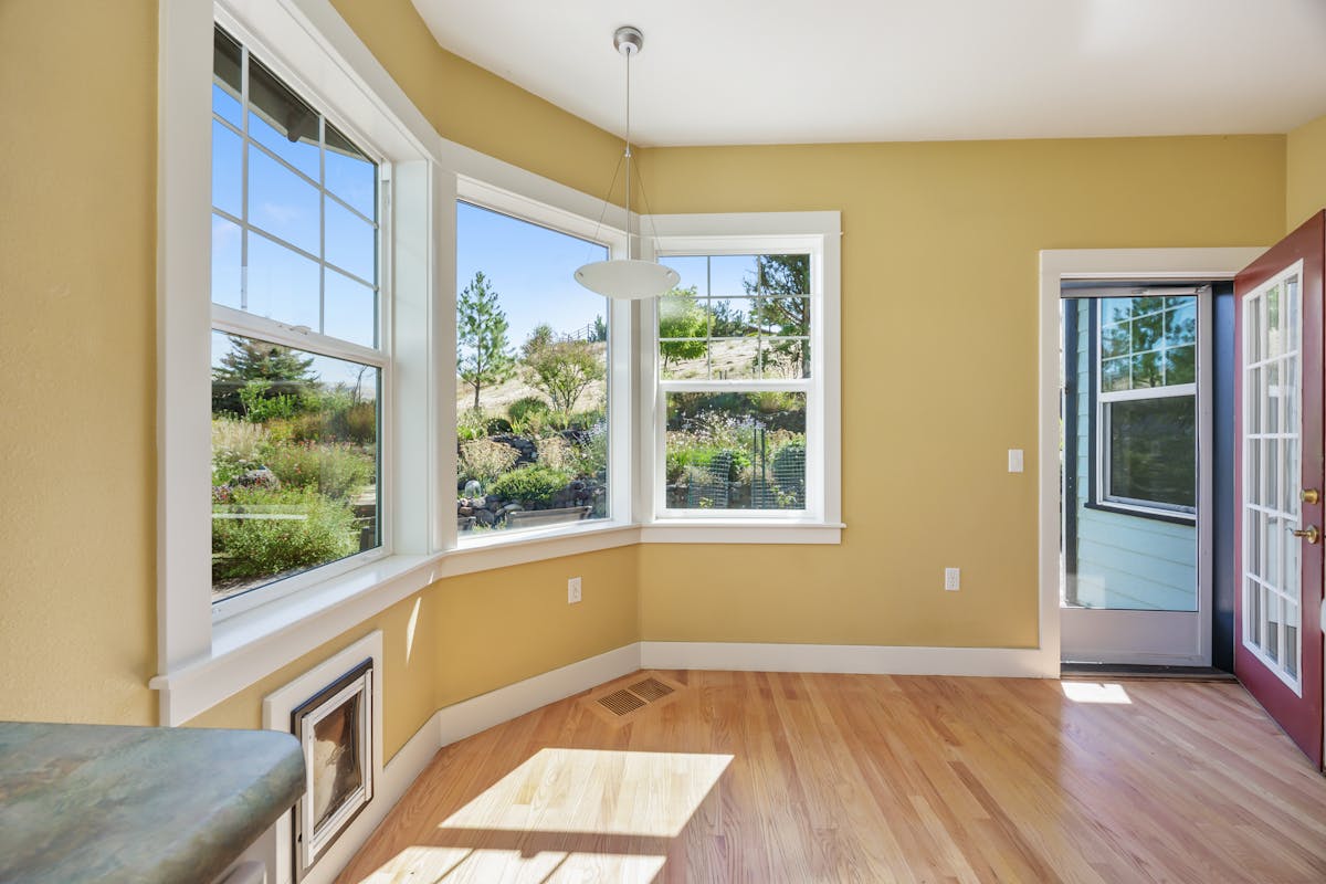 Spacious sunlit room with wooden floors and garden views, creating a serene indoor space.